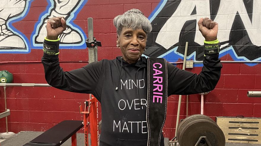 Carrie Reese flexing triumphantly in Vacaville’s Old Skool Gym with her weightlifting belt draped over her shoulder.