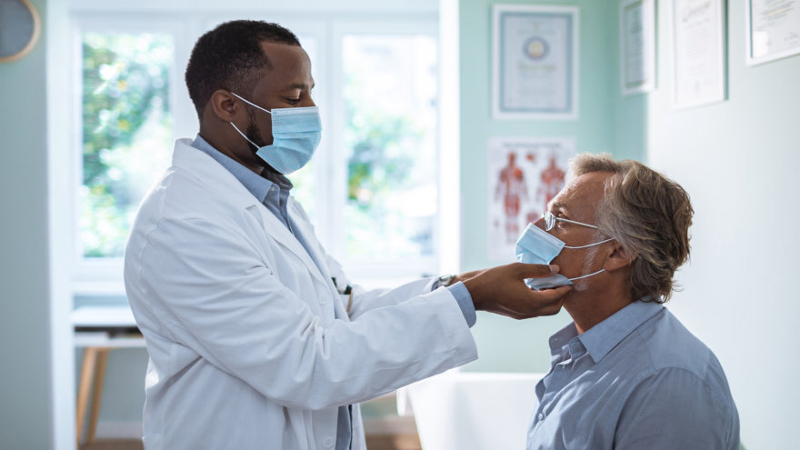 A doctor examining a man's neck in a doctor's office.